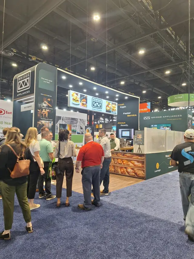 Trade show exhibit with an audience gathered around the booth